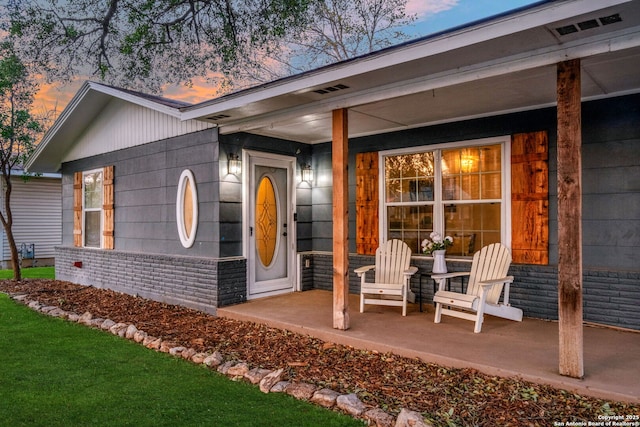 property entrance with brick siding and covered porch