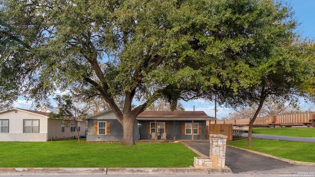 single story home with a front yard, fence, covered porch, and aphalt driveway