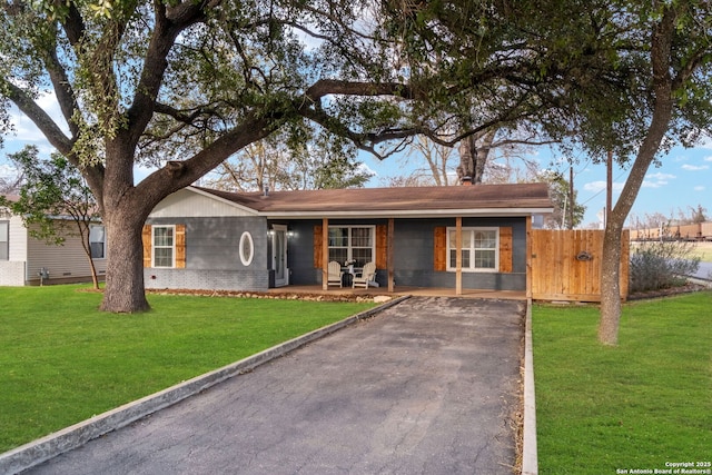 ranch-style house featuring a front yard, fence, driveway, a porch, and brick siding