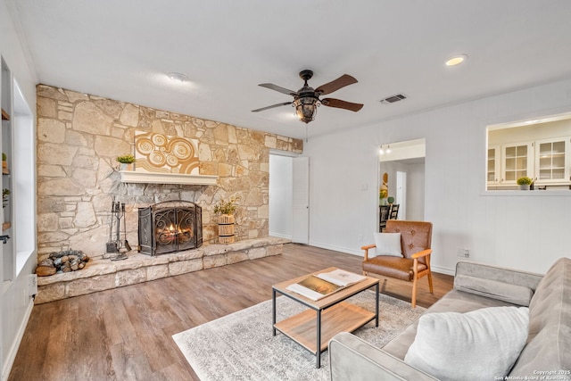 unfurnished living room featuring a ceiling fan, wood finished floors, a fireplace, and visible vents