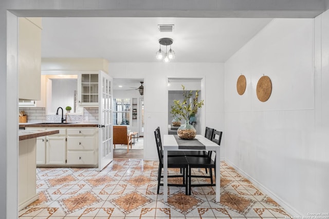 dining room with ceiling fan with notable chandelier, light tile patterned floors, baseboards, and visible vents