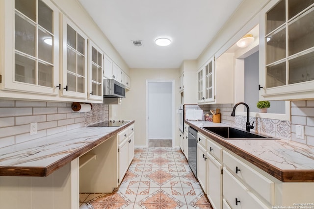 kitchen featuring visible vents, a sink, tasteful backsplash, stainless steel appliances, and light tile patterned flooring