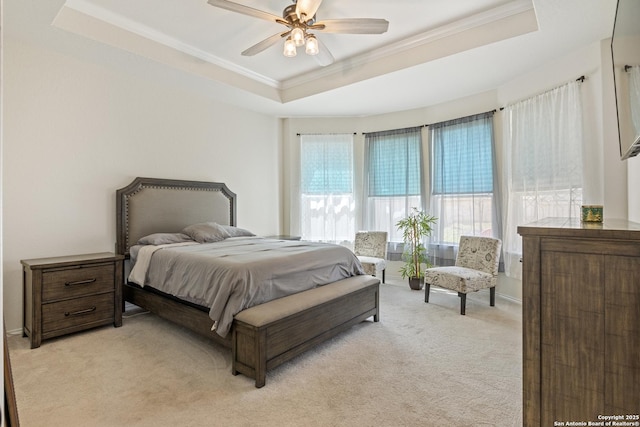 bedroom with a ceiling fan, baseboards, a tray ceiling, light carpet, and crown molding