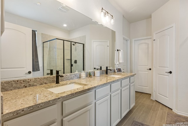 bathroom featuring double vanity, visible vents, a stall shower, and a sink