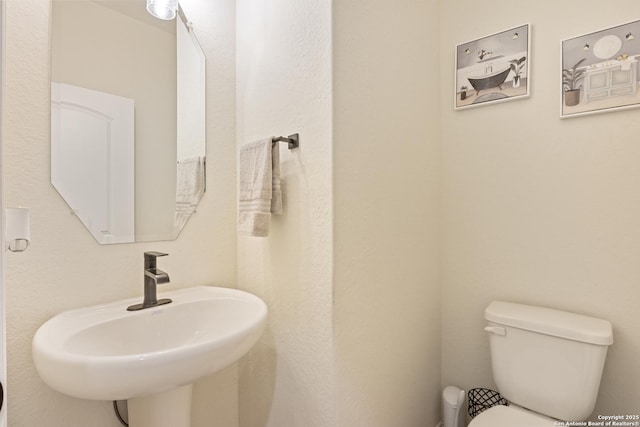 half bath featuring toilet and a sink