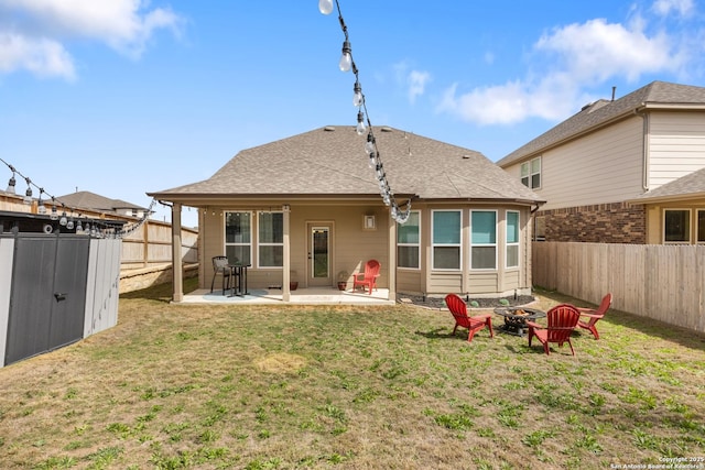 back of property with an outbuilding, an outdoor fire pit, a yard, a fenced backyard, and a patio area