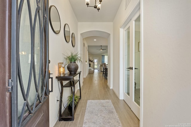 hall with arched walkways, french doors, baseboards, and wood finish floors