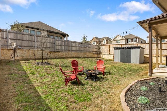 view of yard featuring a shed, an outdoor fire pit, a fenced backyard, and an outdoor structure