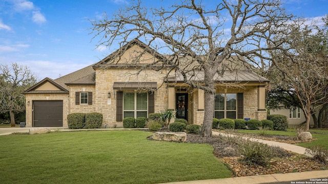 view of front of home with a front lawn, roof with shingles, a garage, stone siding, and driveway