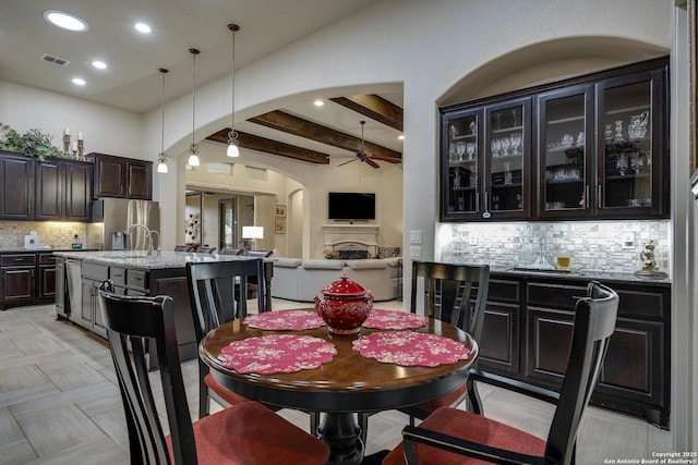 dining area with ceiling fan, beamed ceiling, recessed lighting, a fireplace, and arched walkways