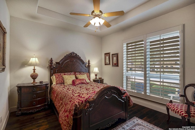 bedroom featuring a ceiling fan, a raised ceiling, baseboards, and hardwood / wood-style floors