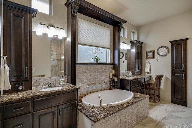 bathroom with a garden tub, two vanities, tasteful backsplash, and a sink