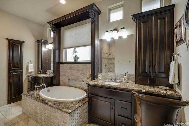 full bathroom with a bath, marble finish floor, vanity, and ornate columns