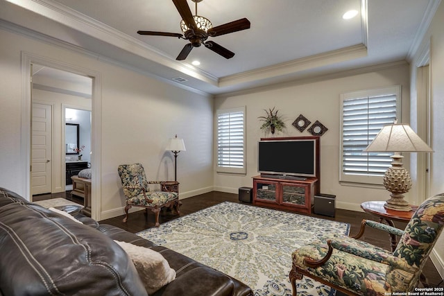 living area featuring baseboards, crown molding, a tray ceiling, and wood finished floors