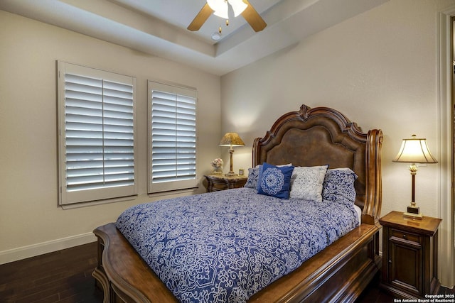 bedroom with a tray ceiling, wood finished floors, baseboards, and ceiling fan