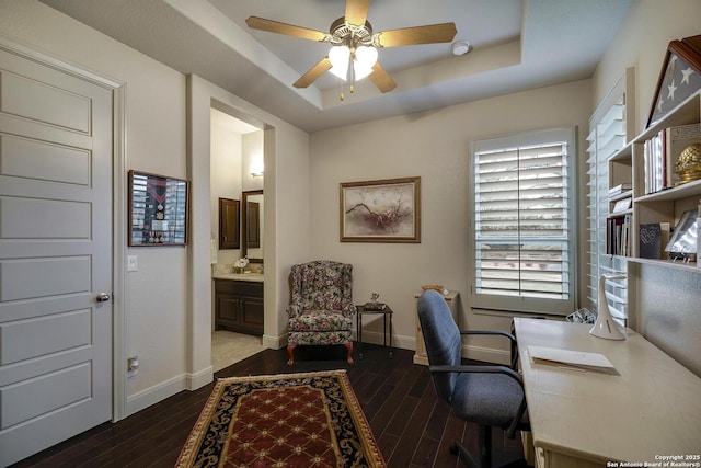 office area featuring dark wood finished floors, ceiling fan, a raised ceiling, and baseboards