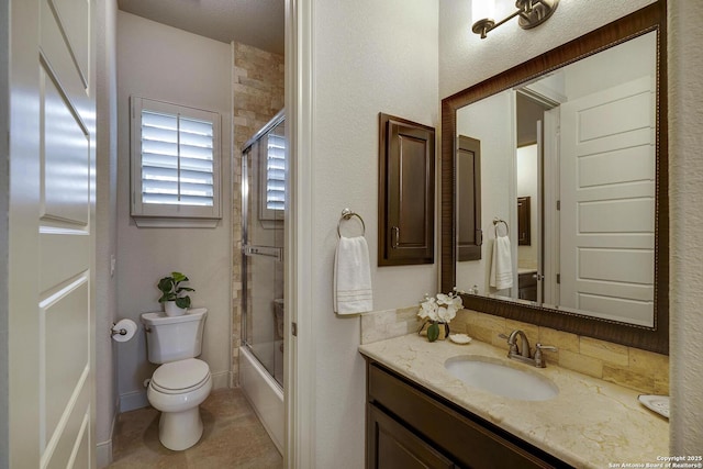 bathroom with bath / shower combo with glass door, toilet, vanity, and tile patterned flooring