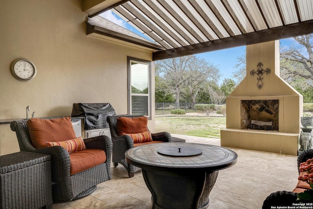 view of patio with area for grilling, exterior fireplace, and fence