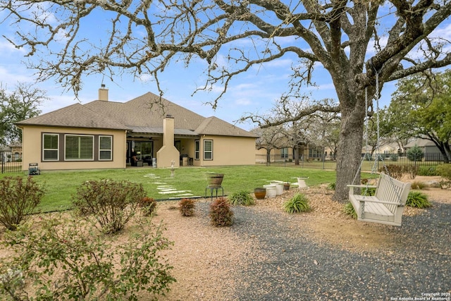 back of house featuring stucco siding, a lawn, a chimney, and fence