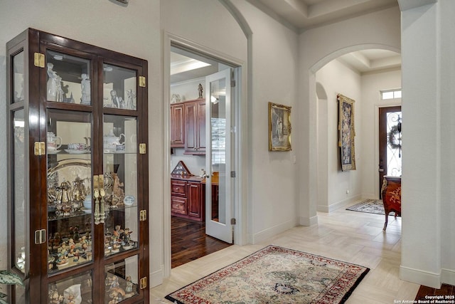 foyer entrance with parquet flooring, baseboards, and arched walkways