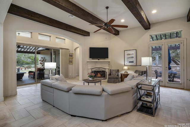 living area featuring visible vents, beam ceiling, recessed lighting, arched walkways, and a lit fireplace