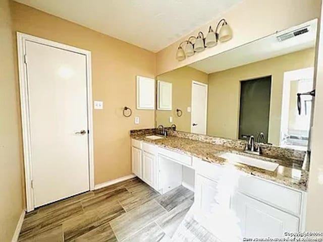 full bath with wood tiled floor, double vanity, visible vents, and a sink