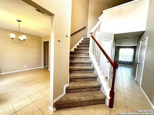 staircase with tile patterned floors, baseboards, a notable chandelier, and a textured ceiling