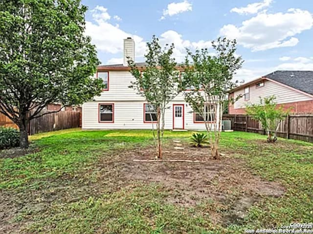 back of house featuring a lawn, a fenced backyard, and a chimney