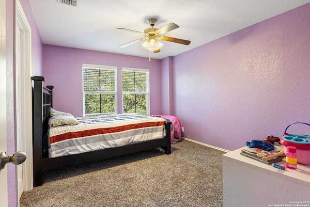 carpeted bedroom with visible vents, baseboards, a ceiling fan, and a textured wall