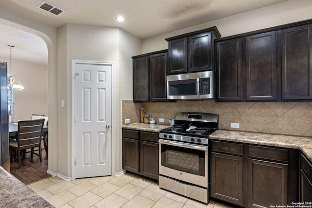 kitchen with visible vents, tasteful backsplash, stainless steel appliances, arched walkways, and light tile patterned flooring