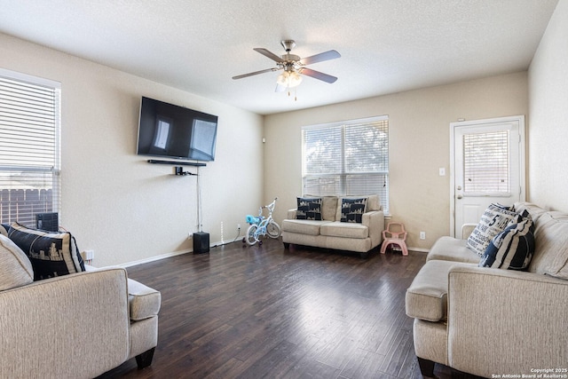 living room with baseboards, a ceiling fan, dark wood-style flooring, and a textured ceiling