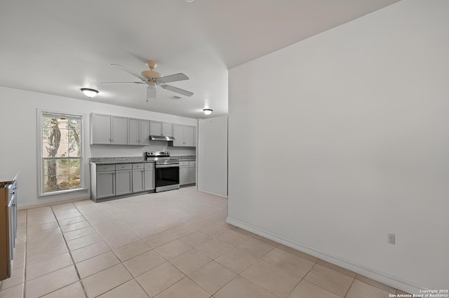 kitchen with gray cabinetry, under cabinet range hood, light tile patterned floors, stainless steel electric range oven, and ceiling fan