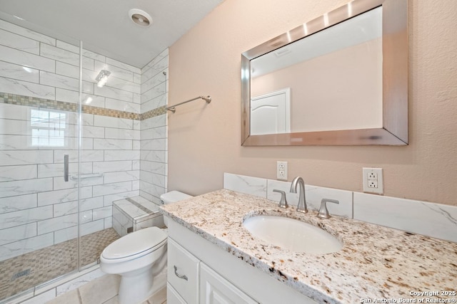 bathroom featuring vanity, a shower stall, and toilet