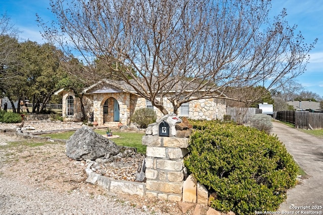 view of front of property with stone siding and fence