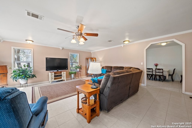 living area featuring light tile patterned floors, visible vents, arched walkways, and crown molding