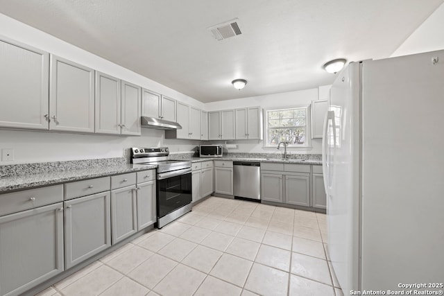 kitchen featuring visible vents, gray cabinetry, under cabinet range hood, stainless steel appliances, and a sink