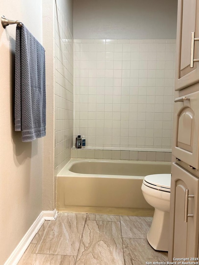 bathroom featuring shower / tub combination, toilet, and baseboards