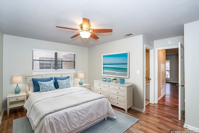 bedroom with multiple windows, wood finished floors, visible vents, and baseboards