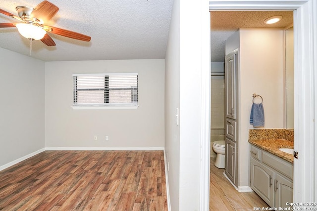 bathroom featuring toilet, vanity, wood finished floors, a textured ceiling, and a ceiling fan