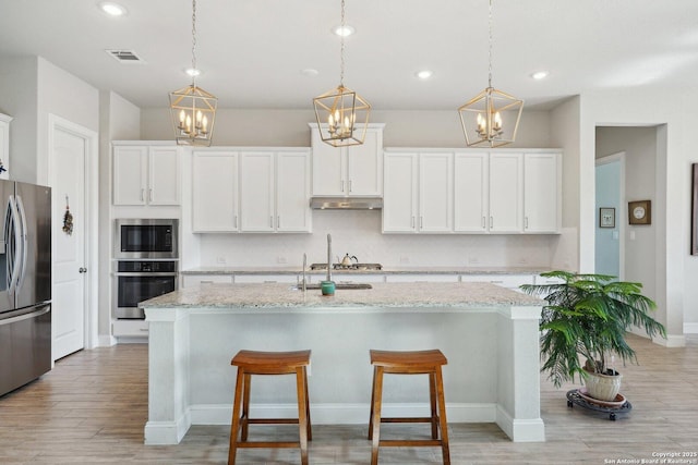 12519 Upton Park, San Antonio, TX 78253 - kitchen featuring visible vents, light wood-style floors, under cabinet range hood, appliances with stainless steel finishes, and tasteful backsplash