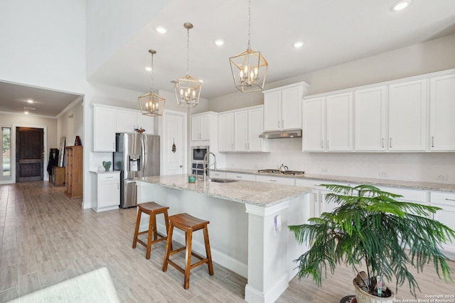 12519 Upton Park, San Antonio, TX 78253 - kitchen featuring a kitchen island with sink, a sink, under cabinet range hood, appliances with stainless steel finishes, and a kitchen bar