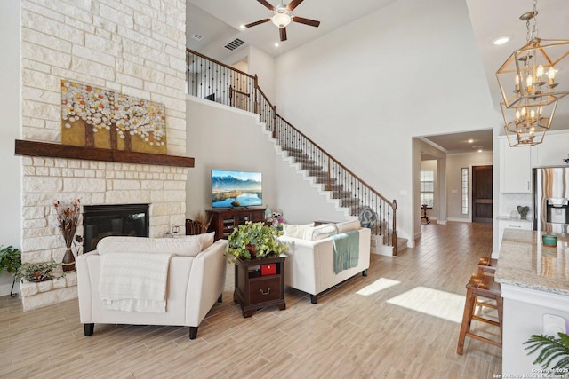12519 Upton Park, San Antonio, TX 78253 - living room with light wood-type flooring, visible vents, ceiling fan with notable chandelier, stairway, and a stone fireplace