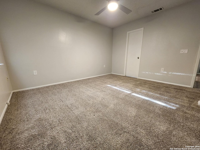 carpeted empty room with baseboards, visible vents, and ceiling fan