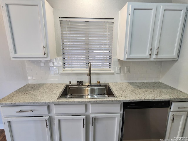 kitchen featuring tasteful backsplash, a sink, white cabinetry, and stainless steel dishwasher