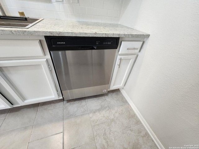 interior details featuring light stone counters, baseboards, stainless steel dishwasher, and white cabinetry