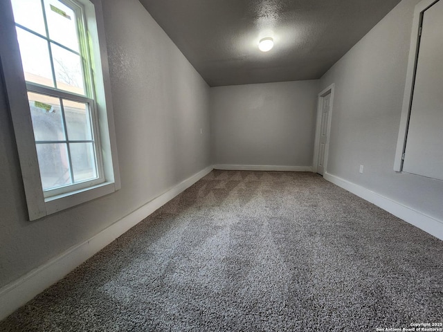 empty room with carpet flooring, baseboards, and a textured ceiling