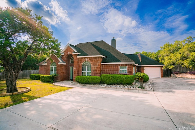 view of front facade featuring fence, concrete driveway, an attached garage, brick siding, and a chimney