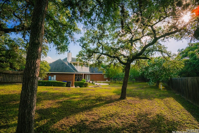 view of yard featuring a balcony and a fenced backyard