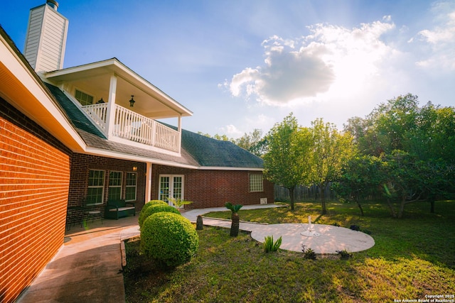 view of yard with a patio area, french doors, and a balcony