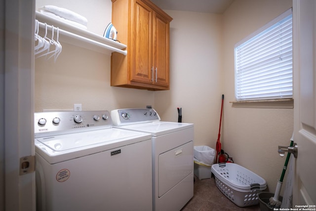 clothes washing area with dark tile patterned floors, cabinet space, and washing machine and clothes dryer